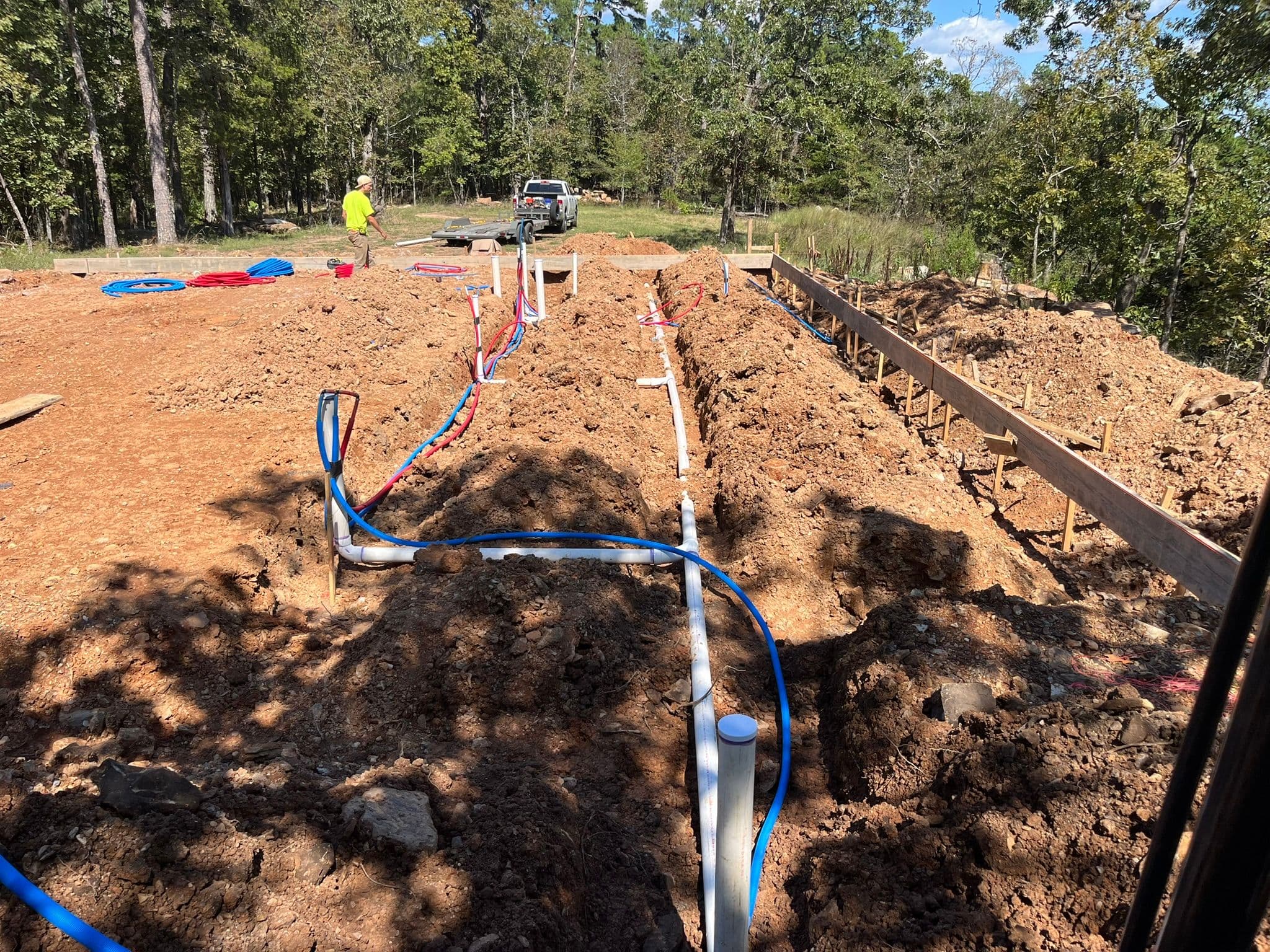 Construction site with excavated trench and plumbing installation for new building foundation.
